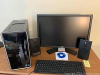Full setup photo showing Dell desktop tower, Altec Lansing speakers, Dell 24 inch monitor, keyboard, mouse, and installation CD on wooden surface