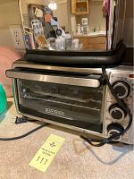 Black & Decker toaster oven on a countertop showing front glass door, control dials and brand label.