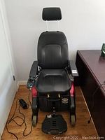 Full front view of electric wheelchair showing seat, headrest, armrests, joystick mount and footrest