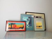Four framed art prints on a surface, showing variety of styles and sizes.