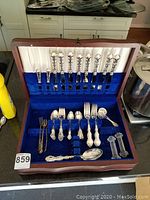 Open wooden chest with lid showing knives in velvet slots and utensils below