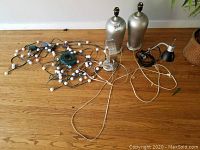 Full view of the two silver lamps, string lights, vanity mirror and desk lamp arranged on the floor.