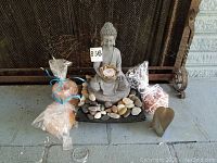 Photo showing the complete set of Buddha statue, salt candle holders, and glass decor on a tiled floor.