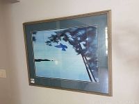 Framed Caroline Millard artwork hanging on an off-white wall, showing full view of the piece with some reflections