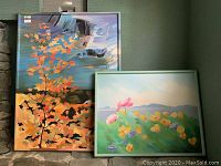 First image shows both paintings propped against a wall, one stacked behind the other, providing an overall view of the lot.