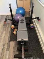 Overview of York weight bench with dumbbells and exercise balls placed around it.