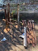 Four assembled metal screw jacks with threaded rods and base plates alongside loose extension rods