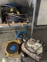 Photo of Coleman air compressor, hoses and yellow crate of cutting discs in a workshop environment.