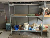 Front view of one metal shelving unit with wooden shelves holding various containers and tools.