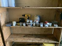Wide shot of shelf with DeWalt drill, charger, battery and assortment of hardware containers and packaging