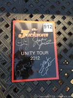 Photo of the front cover of The Jacksons Unity Tour 2012 signed photo book showing four visible silver signatures.