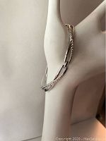 Side view of silver crystal infinity bracelet displayed on hand mannequin showing crystal embellishments along part of the links.