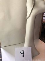 Silver crystal bracelet displayed on white stand, showing full length and clasp.