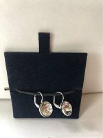 Front view of Swarovski silver earrings with clear round crystals mounted in silver metal setting and lever-back clasps on dark blue holder.