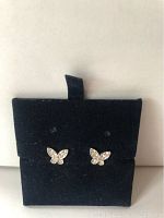 Front view of the pair of silver butterfly earrings on a black velvet holder.