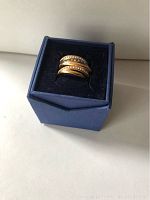 Swarovski rose gold-tone ring with clear crystals shown from a slight angle inside a blue box with black velvet interior.