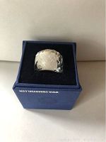 Close-up photos of Swarovski crystal ring, showing wide faceted clear crystal on rose gold-tone band, displayed in blue Swarovski box with black velvet interior.