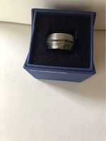 Close-up view of the silver-tone Swarovski ring with black crystals inside the blue Swarovski box with black velvet interior.