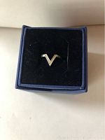 Front view of the Swarovski silver V ring in its navy blue box with a black velvet insert.