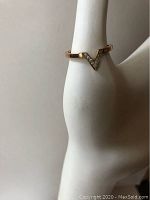 Close-up of the Swarovski V ring worn on a hand display, showing the rose gold color and crystal details.