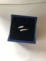 Silver spiral ring with clear Swarovski crystals displayed on black cushion inside blue box.