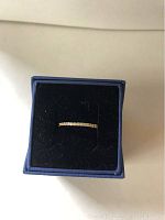 Gold-tone Swarovski crystal ring displayed in blue jewelry box with black velvet interior.