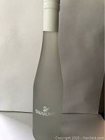 Full view of the frosted glass bottle with white cap and Swarovski name and swan logo.