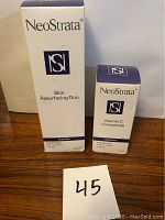 Two boxed NeoStrata skincare products: Skin Resurfacing Duo and Vitamin C Concentrate on wooden surface, with lot number card 45 visible.