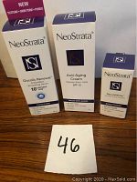 Three boxed NeoStrata skincare products including Glycolic Renewal Smoothing Serum, Anti-Aging Cream with SPF 15, and SecureWhite Anti Dark Circle Complex, placed on a wooden surface with lot number.
