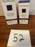 Two boxed NeoStrata eye cream products labeled Anti-Aging Eye Cream and AquaYouth Anti-Wrinkle Eye Cream placed on wooden surface.