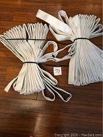 Top-view photo showing two large folded white fire hose bunches placed on a wooden floor, bands securing the hoses visible.