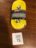 Front view of the Coleman's yellow tow strap in packaging with label showing brand and product details, hooks visible.
