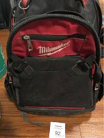 Front view of the Milwaukee tool knapsack showing the red and black color scheme and logo on front pocket.