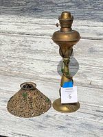 Antique brass oil lamp and its pierced brass shade displayed separately on a wooden surface.