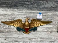 Front view of the antique cast metal American eagle wall plaque with wings spread and red shield in talons.