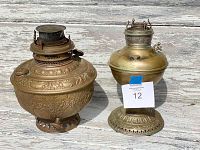 Pair of brass antique oil lamps placed side by side showing different designs and shapes.