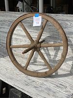 Full view of the antique wooden wheelbarrow wheel showing the six spokes and wooden rim.