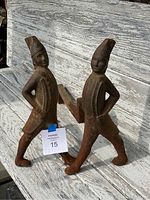 Pair of cast iron andirons shaped as Hessian soldiers with hands on hips, showing overall worn surface and rust.
