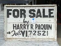 Front view of an antique real estate sign with black text on white wood reading 'FOR SALE by HARRY R. PAQUIN Tel. VI 7-2521'.