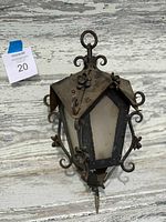 Front and side view of antique hanging lamp showing metal frame with floral and scroll decoration, and frosted glass panels.