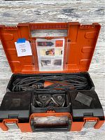 Fein MultiMaster Top multi-tool with power cord, sanding attachments, and instruction manual inside an orange and black plastic carrying case, viewed from above with the case open.