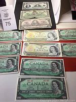 Overview of assorted one dollar bills on red surface with MaxSold lot tag