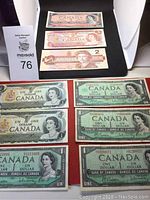Display of three Canadian two-dollar bills from 1954, 1974, and 1986, showing portraits of King George VI and Queen Elizabeth II in varying designs.