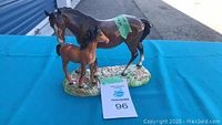 Front and side view of Beswick mare and foal ceramic figurine on blue table with auction tag