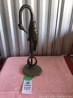 Front view of metal heron sculpture on stone base
