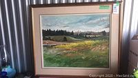 Full view of framed landscape painting leaning in storage unit