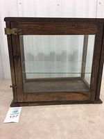 Front view of the antique display case showing wood frame, glass panels, front door with knob and latch.