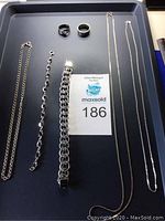 Full view of the 3 necklaces, 2 bracelets, and 2 rings arranged on black tray