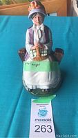 Front view of Royal Doulton figurine "Rest Awhile" showing the elderly woman seated on a wooden bench holding a basket, with a green base.