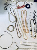 Photo showing a variety of costume jewelry including faux pearl necklaces, beaded bracelets, chain necklaces, black velvet choker, and a silver collar neckpiece.